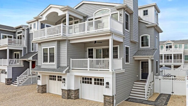 A multi-story residential building with a balcony, a garage, and a stone foundation. - Ultimate Beach Getaway (Long Beach)