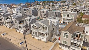 A coastal residential area with multi-story houses featuring balconies and a beach in the foreground. - Ultimate Beach Getaway (Long Beach)