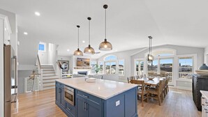 A spacious kitchen with a large island, wooden flooring, and pendant lighting. - Ultimate Beach Getaway (Long Beach)