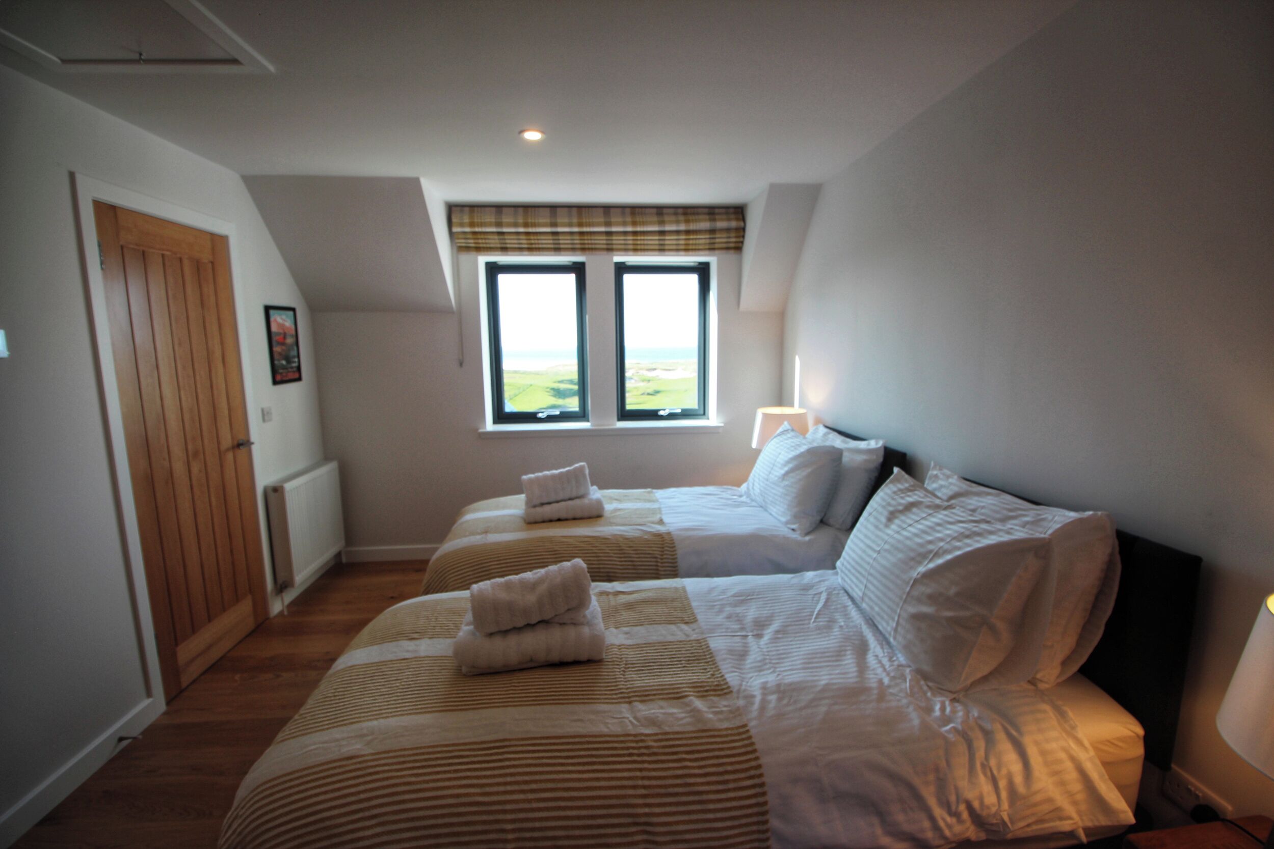 Quarto com duas camas, janela com vista, radiador e porta.