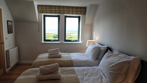 Un dormitorio con dos camas, vistas al exterior por una ventana y un radiador en la pared.