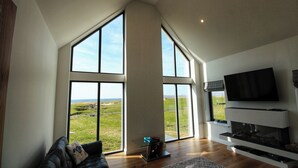 Amplia sala de estar con ventanas grandes, televisor de pantalla plana y chimenea.