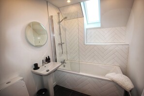 A bathroom with a white sink, a mirror, a glass-enclosed shower, and a bathtub. - One Sea (Harris)