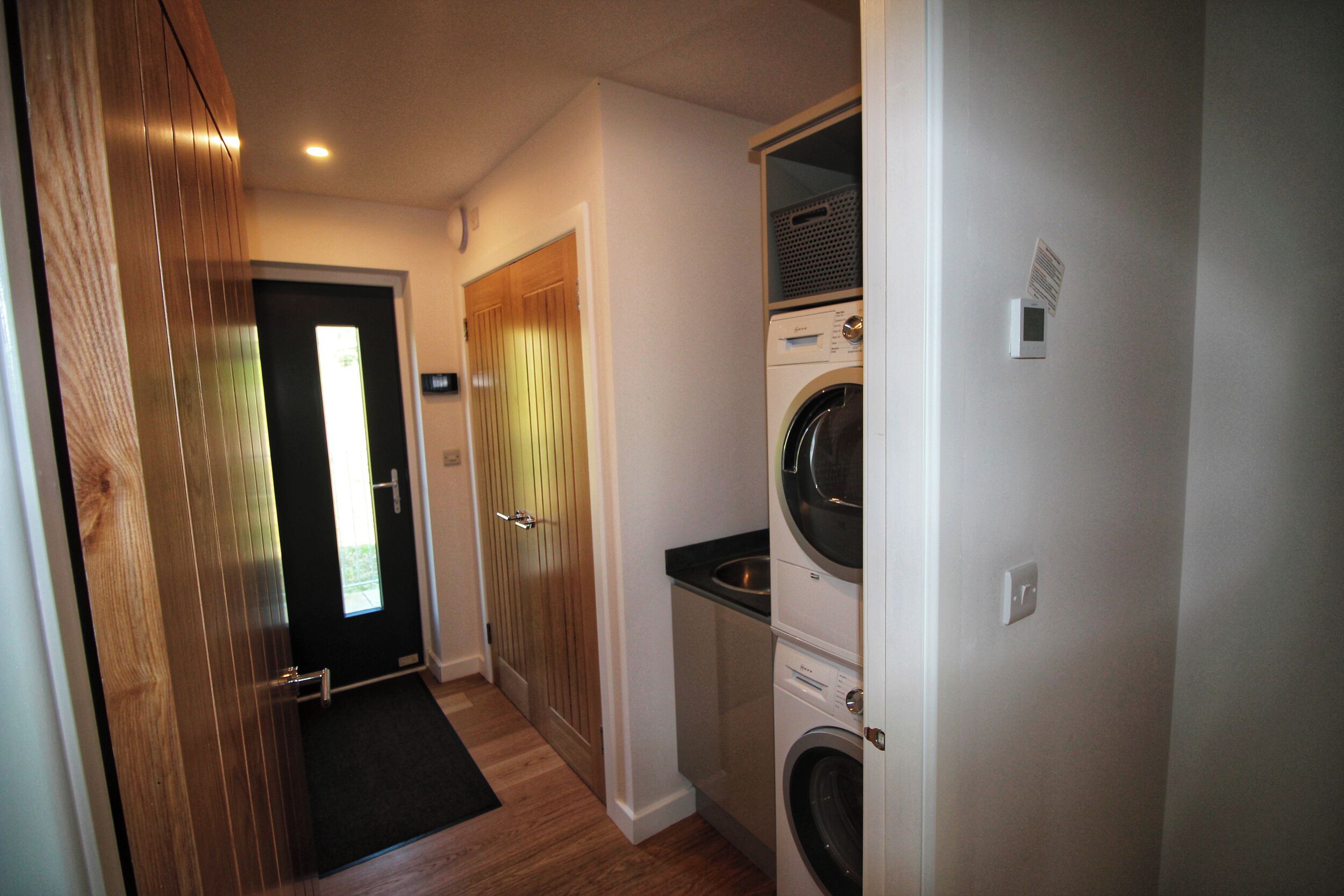 A laundry room with a washing machine, dryer, and a door leading to a hallway.
