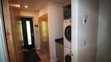 A laundry room with a washing machine, dryer, and a door leading to a hallway.