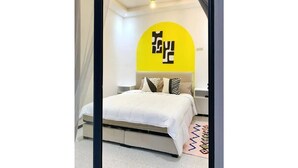 Un dormitorio moderno con cama, pared de acento amarilla y un diseño de techo único.