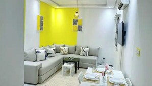 Un salón con sofá, mesa de centro y mesa de comedor dispuesta para una comida.