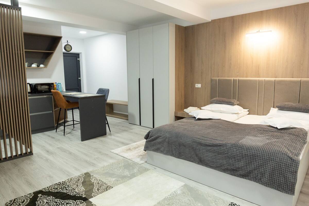 A modern bedroom with a bed, a desk, and a wardrobe.