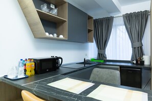 A modern kitchen with a microwave, toaster, and a coffee machine. There are bottles of water and soda on the counter. - Frasin Studios-6 km to Voronet Monastery (Frasin)