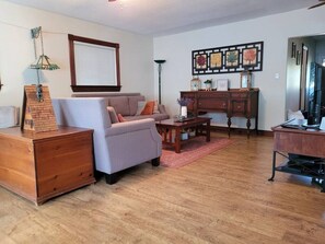 A living room with a sofa, coffee table, wooden dresser, and a desk with a computer.