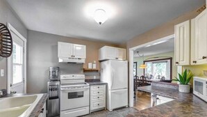 A kitchen with white cabinets, a stove, a refrigerator, and a granite countertop. - Rustic Pines Waterfront Cottage *CLEAR WATER* (Kawartha Lakes)