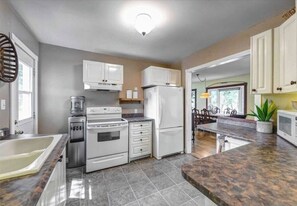 A kitchen with white cabinets, a stove, a refrigerator, and a granite countertop.