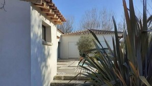 A building with a tiled roof, a garage door, and a staircase leading to a pool area. - Perle rare :Villa de Campagne 140 m2 avec Piscine son pool house & Grand jardin (Le Thor)