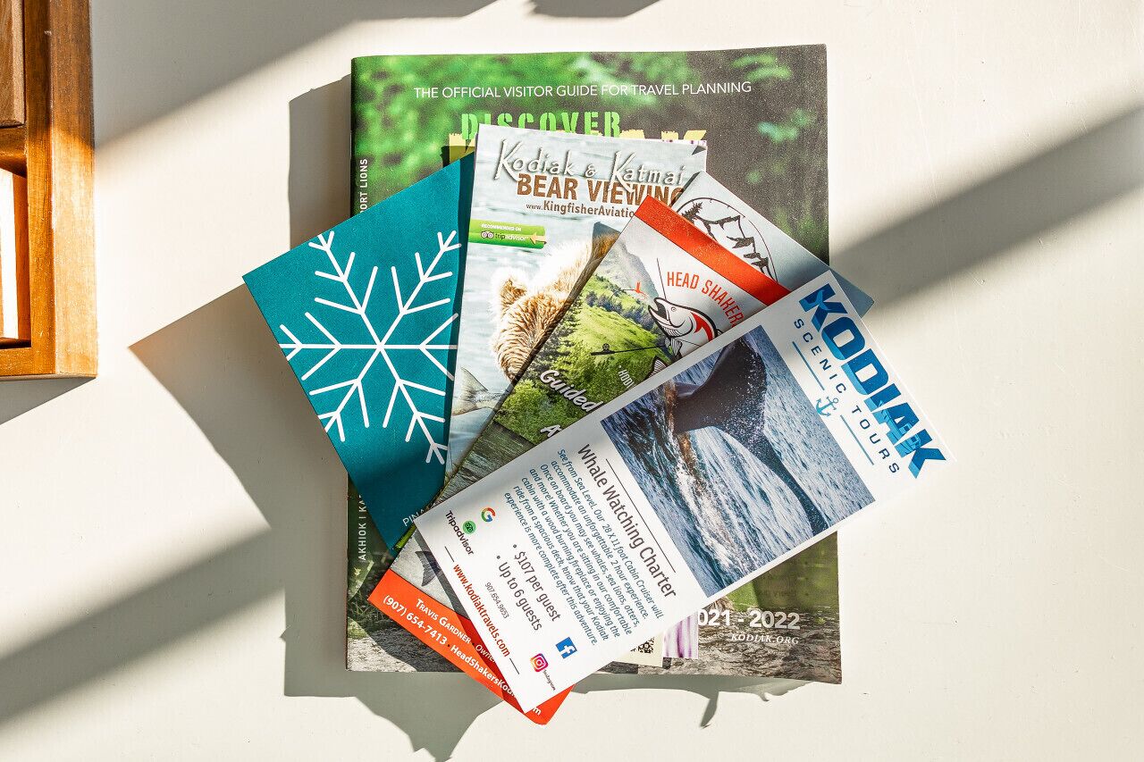 Een verzameling reisbrochures en gidsen, waaronder 'Discover', 'Bear Viewing' en 'KODIAK SCENIC TOURS'.