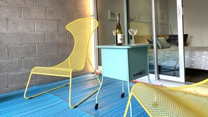 Ein modernes Zimmer mit Backsteinwand, einer Glastür zu einem Bett und einem kleinen Tisch mit Flasche und Glas.
