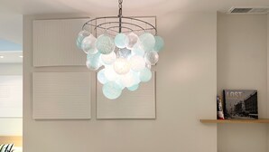 Ein modernes Zimmer mit einer markanten, kugelförmigen Pendelleuchte, einem gerahmten Stadtbild und einem kleinen Regal mit Dekorationen.