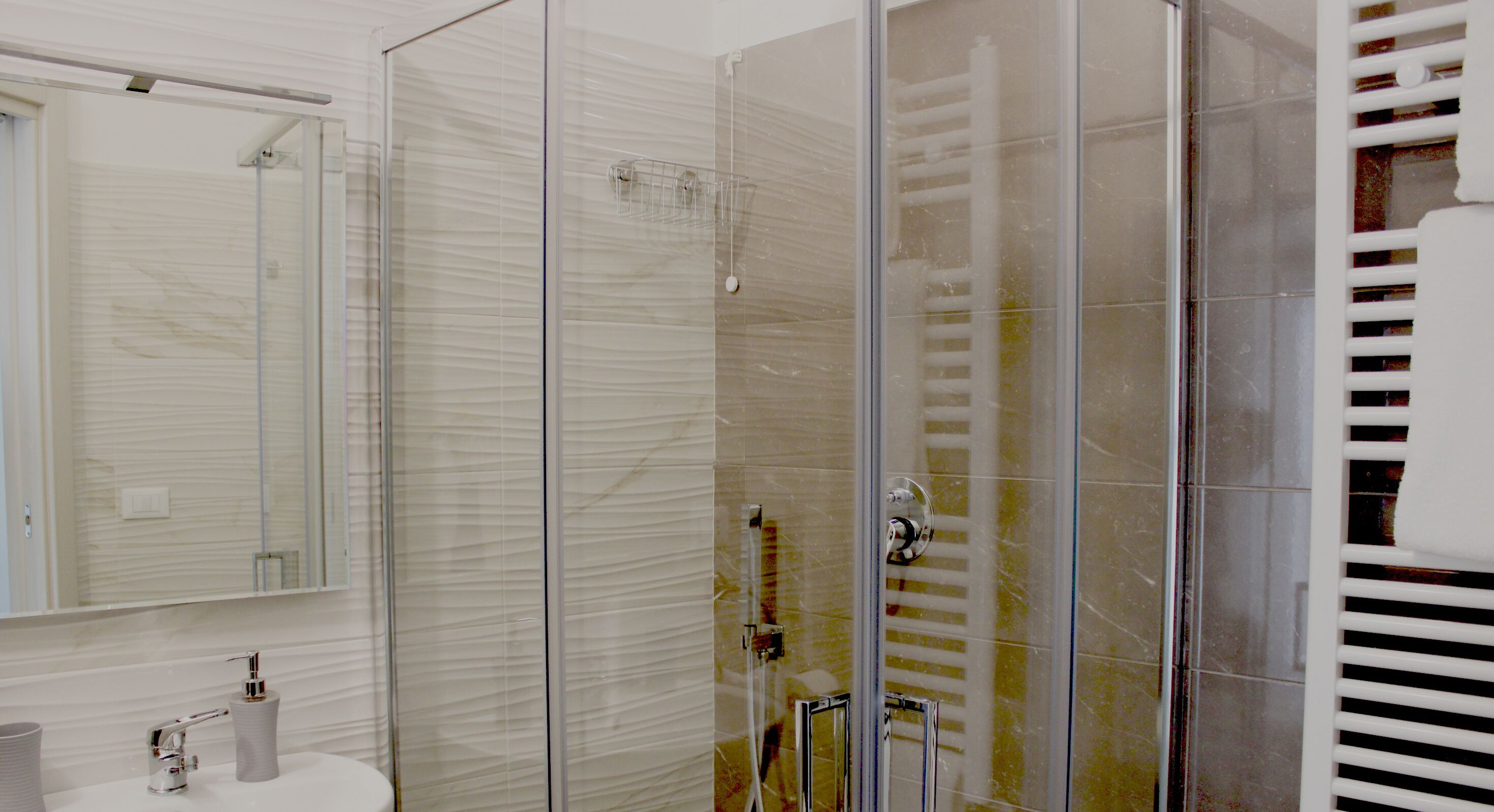 Een moderne badkamer met een douchecabine van glas, een witte wastafel en een spiegel.