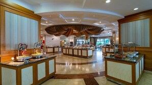 A spacious lobby with a central island featuring a buffet, surrounded by seating areas and a high ceiling with recessed lighting. - Palmeras Beach Hotel (Alanya)