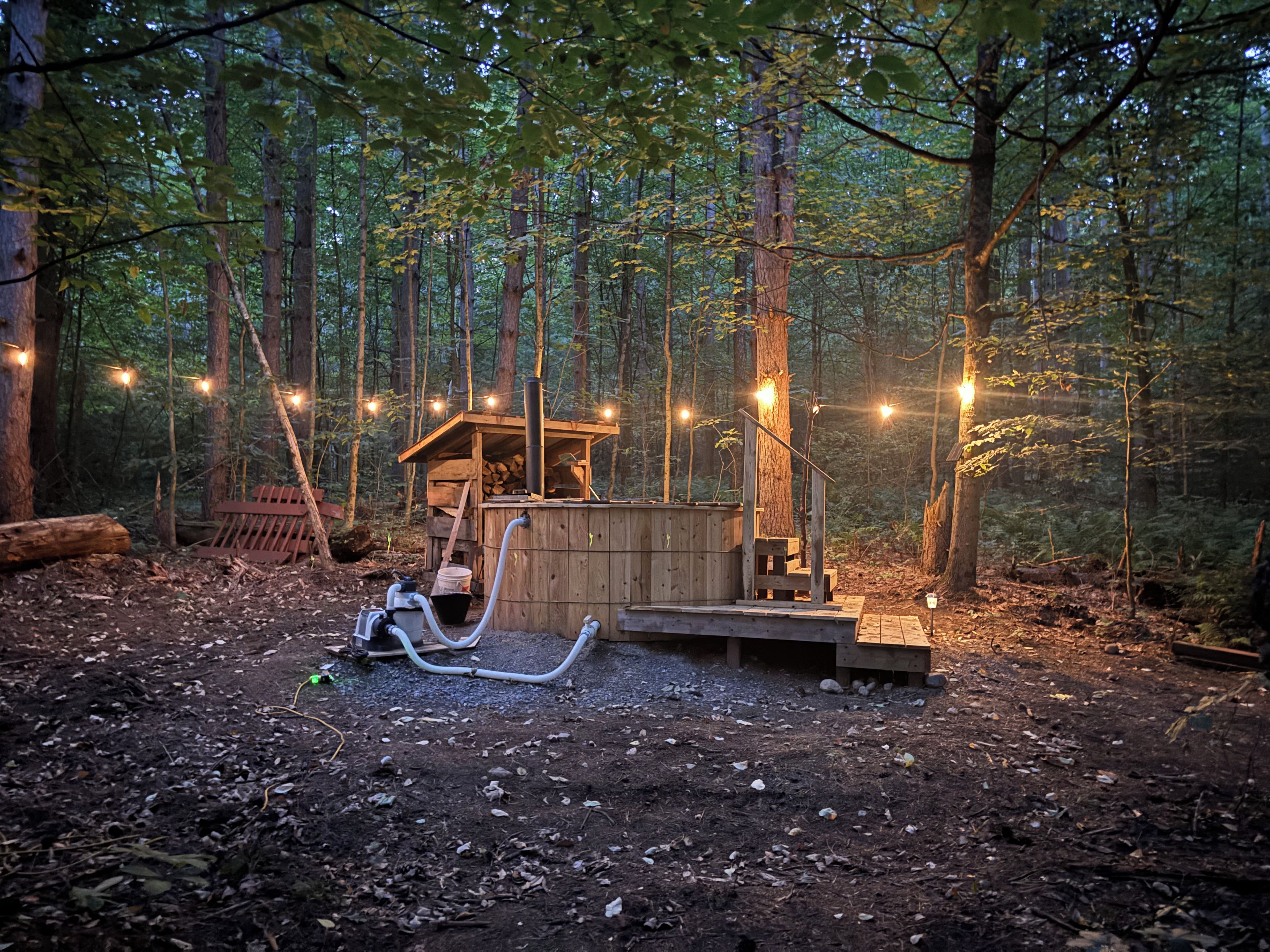 A rustic wooden cabin surrounded by a forest with string lights.