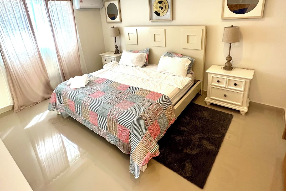 Un dormitorio moderno con una cama grande, mesitas de noche y un ventilador de techo.