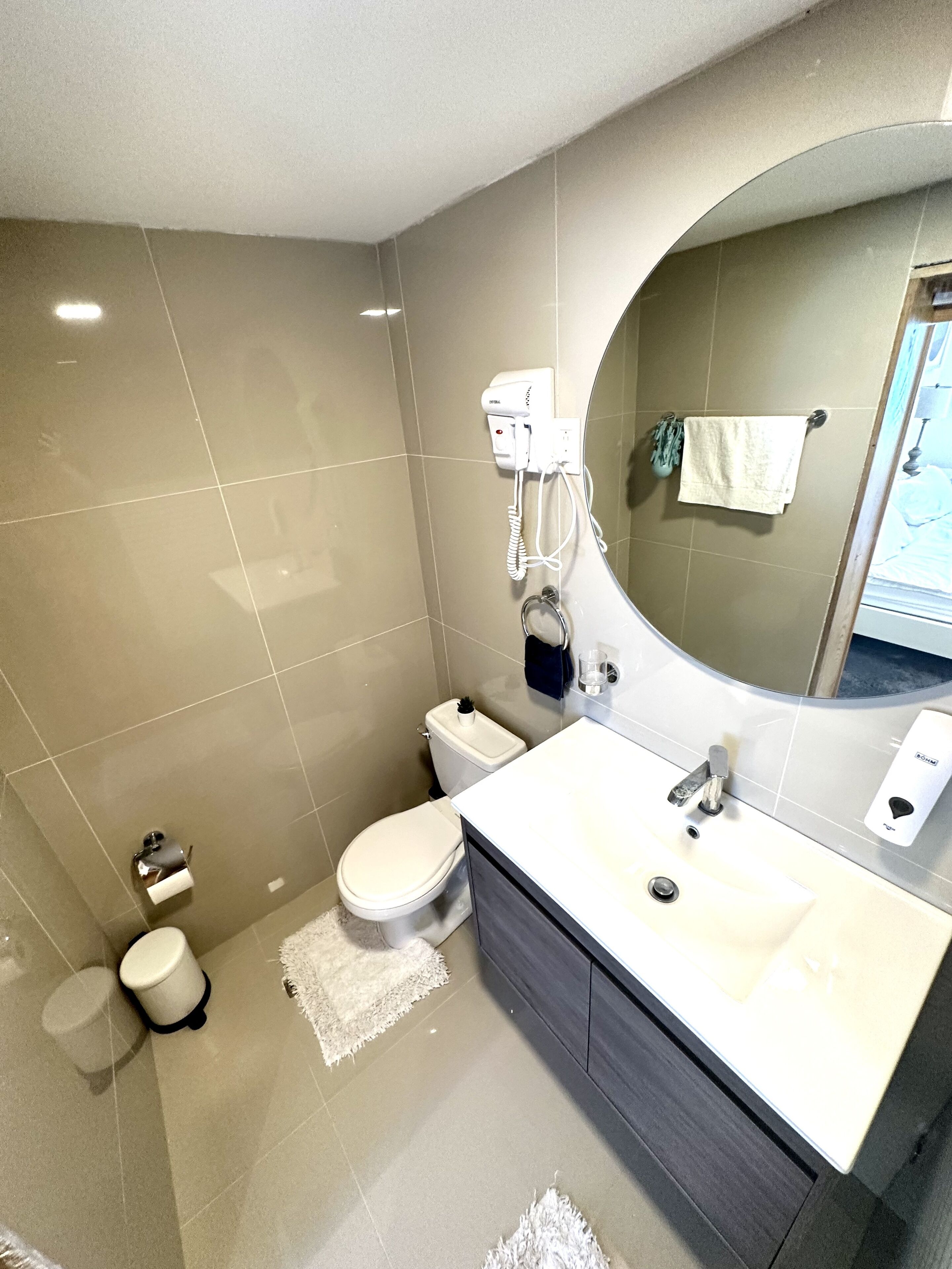 A modern bathroom with a toilet, sink, and a hairdryer on the wall.