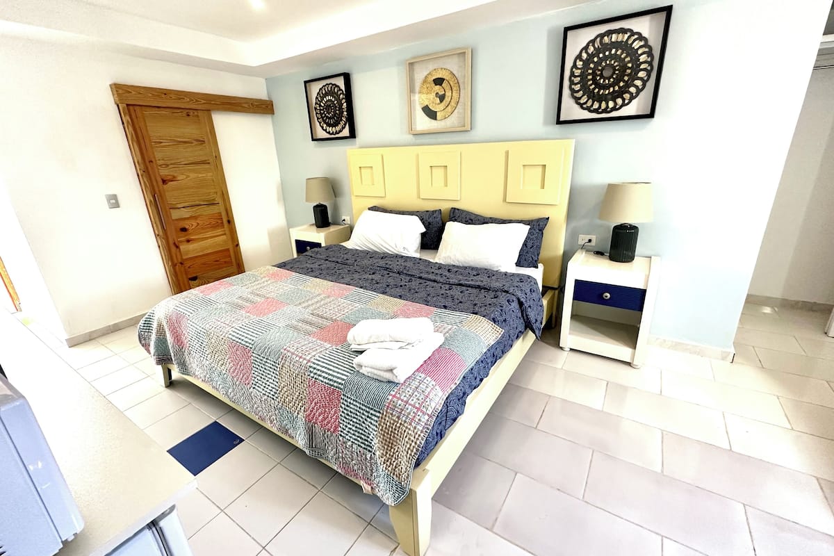 Un dormitorio con cama, mesitas de noche, un armario de madera y decoración en la pared.