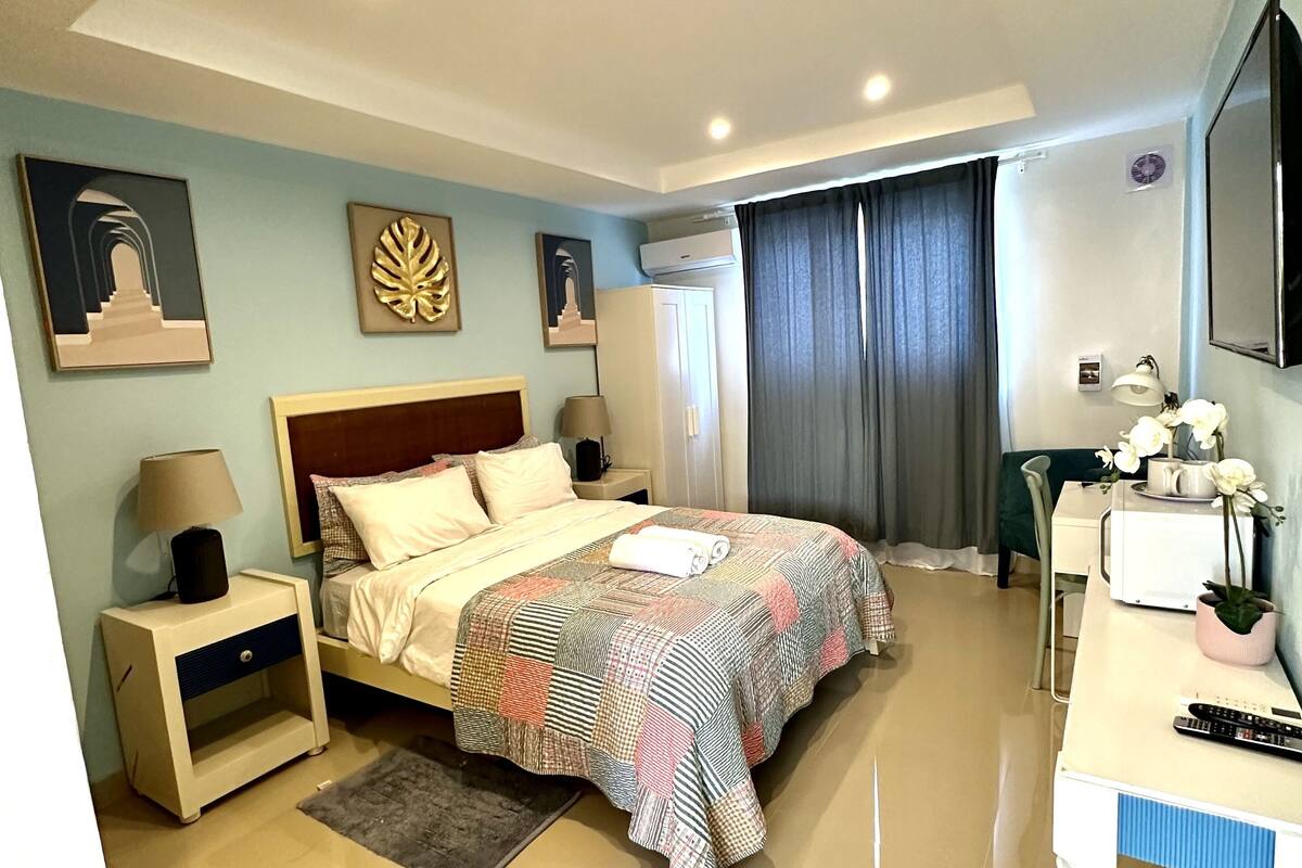Un dormitorio moderno con una cama grande, mesitas de noche, un escritorio y un televisor de pantalla plana.
