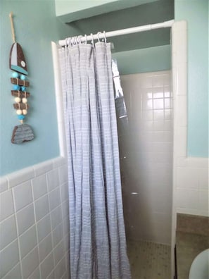 Un baño con cortina de ducha, paredes de azulejos y un adorno colgante.