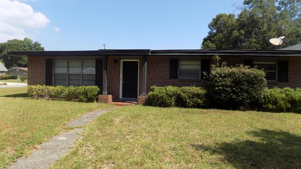A single-story brick house with a front door, two windows, and a satellite dish.