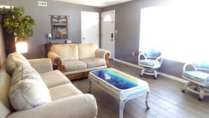 A living room with a sofa, armchairs, a coffee table, and a view of the outdoors.