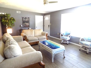 A living room with a sofa, armchairs, a coffee table, and a view of the outdoors.