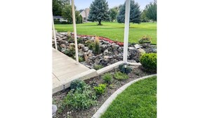 A covered patio with a stone border, a lawn, and a large tree in the background. - Cheery and Bright four Bedroom Walkout Basement (Highland)