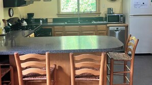A kitchen with a central island, wooden chairs, a stove, a sink, and a refrigerator. - Peaceful and private cabin close to the Little Buffalo River. (Jasper)