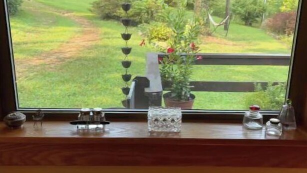A window with a view of a garden, a wooden shelf with salt and pepper shakers, and a small decorative item. - Peaceful and private cabin close to the Little Buffalo River. (Jasper)