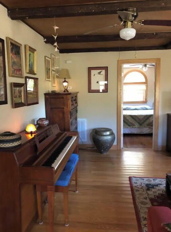 Une pièce avec un piano en bois, un grand vase et des tableaux encadrés accrochés au mur.