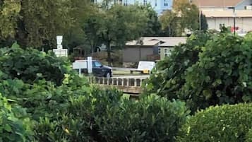 Un quartier résidentiel où se trouve une maison remarquable, avec un toit rouge et des murs blancs, entourée d’une végétation luxuriante et d’arbres.