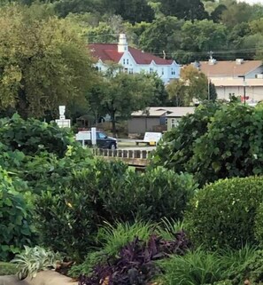 Un quartier résidentiel où se trouve une maison remarquable, avec un toit rouge et des murs blancs, entourée d’une végétation luxuriante et d’arbres.