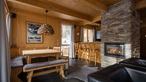 A cozy cabin interior with a stone fireplace, wooden furniture, and a dining area. - Chalet #7 with IR-sauna (Turrach)
