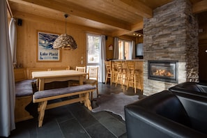 Een gezellig interieur van een blokhut met een stenen openhaard, houten meubels en een eethoek.