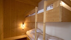 Ein Schlafraum mit Etagenbetten, Holzwänden und einer Wandleuchte.
