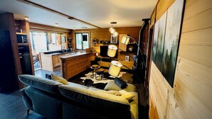 Ein gemütliches Blockhaus-Interieur mit Holzausstattung, einer Couch, einem Esstisch und einer Küchenzeile.