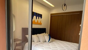 Ein Schlafzimmer mit Bett, einem Holzschrank, einem Bild an der Wand und einer Deckenleuchte.