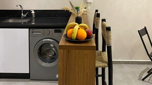 Eine Küche mit Waschmaschine, Spüle und Obstschale auf einer Holzausziehtafel.