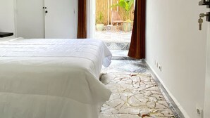 Camera da letto con un letto, una porta e vista su uno spazio esterno con una sedia e piante.
