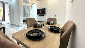 Zona pranzo moderna con tavolo in legno, sedie e televisore a schermo piatto montato a parete.