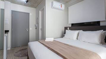 Una camera d'albergo con un letto, un comodino, un armadio, un condizionatore d'aria e una porta.