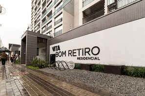 A building with a sign reading 'VITA BOM RETIRO RESIDENCIAL' and a pathway leading to it. - Vita Bom Retiro (São Paulo)