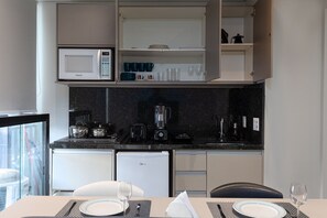 A compact kitchen with a microwave, coffee maker, toaster, and refrigerator.