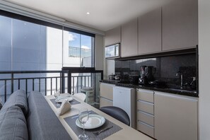 A modern kitchen with a dining area, large windows, and a balcony.