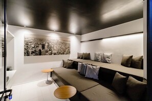 A modern living room with a sectional sofa, a small round table, and a cityscape painting on the wall.